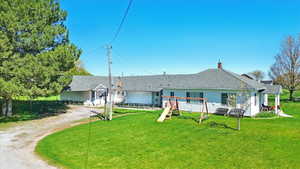 Rear view of house featuring driveway, a lawn, a chimney, and a shingled roof