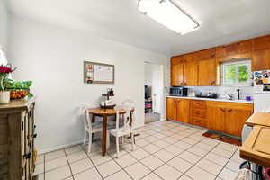 Back Unit's Kitchen featuring freestanding refrigerator, stainless steel microwave, light countertops, brown cabinets, and a sink