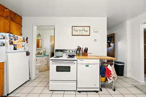 Back Unit's Kitchen with white appliances, brown cabinetry, light tile patterned floors, and light countertops