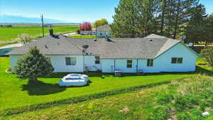 Back of property featuring a lawn, roof with shingles, and central AC unit