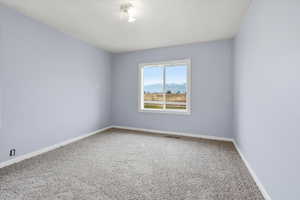 Spare room featuring carpet flooring and baseboards