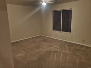 Carpeted empty room with a ceiling fan and baseboards