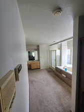 Full bathroom featuring a bath, a stall shower, a textured ceiling, baseboards, and a sink