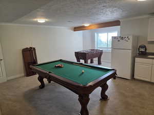 Game room with light carpet, a textured ceiling, pool table, crown molding, and baseboards