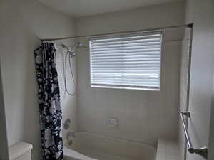 Full bathroom with toilet, plenty of natural light, and shower / bath combo with shower curtain