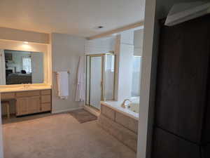 Full bath featuring ensuite bathroom, a shower stall, a tub with jets, vanity, and a textured ceiling