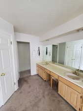 Full bath featuring carpet floors, double vanity, a textured ceiling, and tile patterned floors