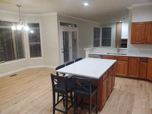 Kitchen featuring a sink, light countertops, light wood-type flooring, crown molding, and recessed lighting