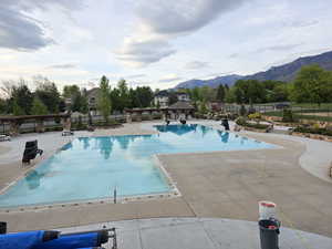 Community pool featuring fence, a mountain view, and a patio area