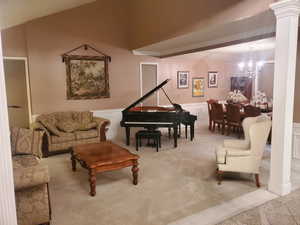 Living room with carpet flooring, a chandelier, decorative columns, wainscoting, and a decorative wall