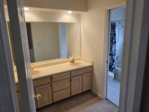 Bathroom featuring double vanity, toilet, and shower / bathtub combination with curtain