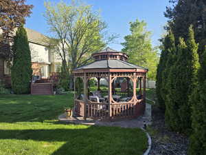 View of grassy yard featuring a gazebo and a wooden deck