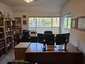 Home office with lofted ceiling and carpet floors