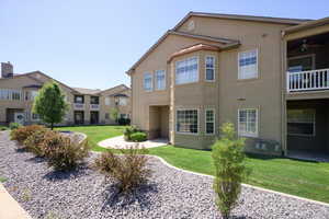 Rear view of property featuring stucco siding, a lawn, and ceiling fan