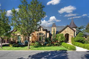 View of front of property with stone siding, a front yard, and a chimney