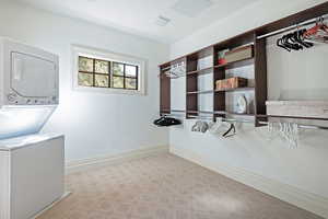 Spacious closet with stacked washing machine and dryer and tile patterned floors