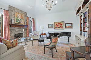 Living room featuring baseboards, a stone fireplace, and a chandelier