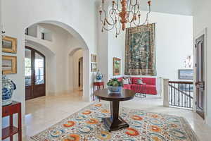 Foyer entrance featuring a high ceiling, light tile patterned floors, a chandelier, baseboards, and arched walkways