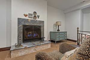 Carpeted living area featuring a premium fireplace and baseboards