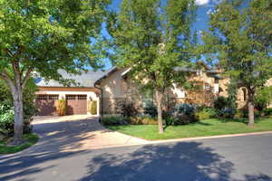 View of front of house with concrete driveway, stone siding, stucco siding, a front yard, and a garage