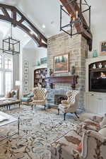 Living room with a chandelier, a stone fireplace, and high vaulted ceiling