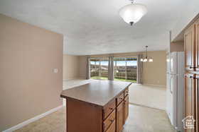 Kitchen with freestanding refrigerator, open floor plan, brown cabinets, and baseboards