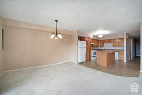 Kitchen with freestanding refrigerator, baseboards, open floor plan, stove, and a kitchen island