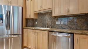 Kitchen with appliances with stainless steel finishes, light brown cabinetry, and a sink
