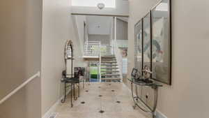 Corridor with a towering ceiling, baseboards, and tile patterned floors