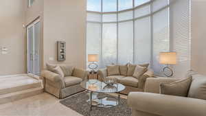 Living area featuring a towering ceiling and light marble finish flooring