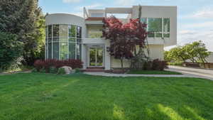 View of front facade featuring stucco siding, a front lawn, and concrete driveway