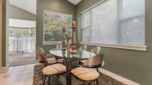 Dining space with vaulted ceiling, tile patterned floors, baseboards, and carpet flooring