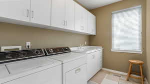 Laundry area featuring cabinet space, washing machine and dryer, baseboards, and light tile patterned floors