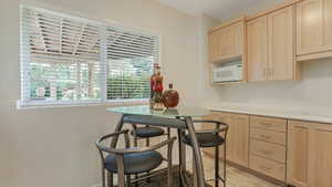 Kitchen featuring light brown cabinets, white microwave, light countertops, and light tile patterned floors