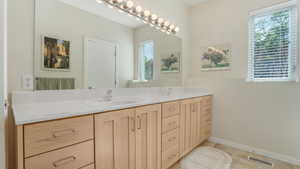 Bathroom with double vanity, tile patterned flooring, and baseboards