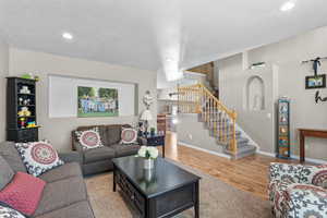 Living area with stairs, recessed lighting, baseboards, wood finished floors, and a textured ceiling
