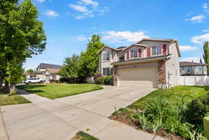 Traditional-style home featuring stone siding, driveway, an attached garage, and stucco siding