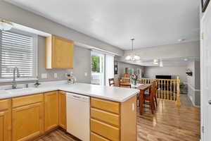 Kitchen with dishwasher, a sink, a peninsula, light wood-style floors, and open floor plan