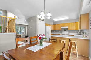 Dining room featuring a chandelier, light wood-style floors, baseboards, a textured ceiling, and stairs