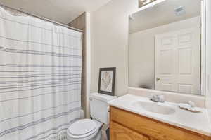 Full bath featuring vanity, toilet, a textured ceiling, and curtained shower