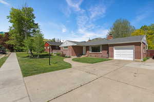 Ranch-style house with brick siding, an attached garage, driveway, and a chimney