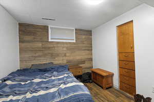 Bedroom featuring wood walls, dark wood-type flooring, and an accent wall