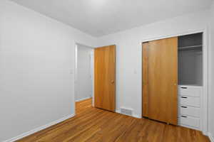 Unfurnished bedroom featuring wood finished floors, a closet, and baseboards