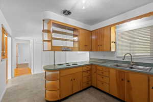 Kitchen featuring a sink, open shelves, a peninsula, white electric stovetop, and light floors