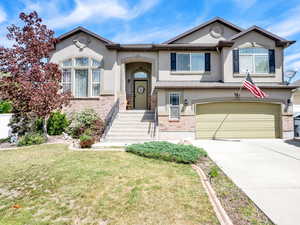 View of front of property with stucco siding, an attached garage, driveway, and a front yard