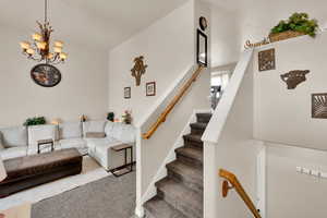 Living room with a chandelier, carpet, and stairs