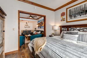 Bedroom with ornamental molding, wood-type flooring, baseboards, and a chandelier