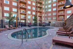Community pool featuring fence and a patio area