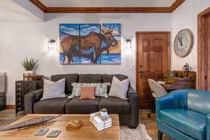 Living room with wood finished floors, ornamental molding, and baseboards