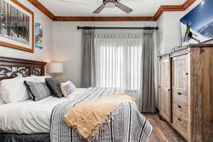 Bedroom with ornamental molding, dark wood finished floors, and a ceiling fan